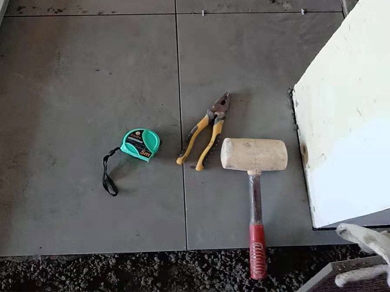 客廳地磚鋪貼：鋪貼的工具包括橡膠錘和粘結(jié)劑。在進(jìn)行施工之前先把所需要的這些材料都整理好放在一旁備用；基層的處理工作對瓷磚的平整度有很大的影響，對于基層要做好清潔工作，還有找平工作。放樣：在進(jìn)行瓷磚的鋪貼工作之前還事先找好垂直線，這樣可以在鋪貼的時候找到瓷磚的水平線，讓瓷磚鋪貼的更加的平整。粘結(jié)劑加水?dāng)嚢杈鶆颍o置10分鐘之后就可以使用。將瓷磚表面的浮灰清除，再在瓷磚背面均勻的涂抹上粘結(jié)劑，按照預(yù)鋪的順序?qū)⒋纱u鋪貼在地面上，最后用橡膠錘輕輕拍打至服帖齊整。