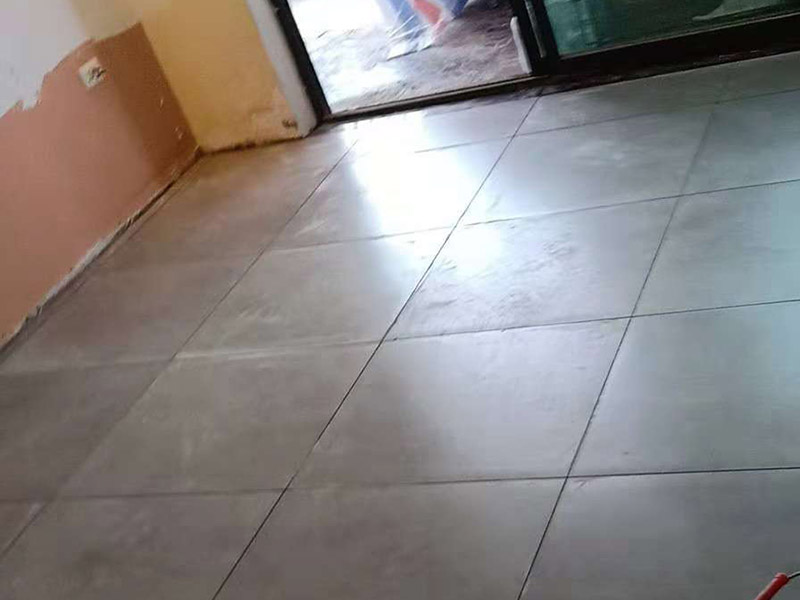客廳地磚鋪貼：鋪貼的工具包括橡膠錘和粘結(jié)劑。在進(jìn)行施工之前先把所需要的這些材料都整理好放在一旁備用；基層的處理工作對瓷磚的平整度有很大的影響，對于基層要做好清潔工作，還有找平工作。放樣：在進(jìn)行瓷磚的鋪貼工作之前還事先找好垂直線，這樣可以在鋪貼的時候找到瓷磚的水平線，讓瓷磚鋪貼的更加的平整。粘結(jié)劑加水?dāng)嚢杈鶆?，靜置10分鐘之后就可以使用。將瓷磚表面的浮灰清除，再在瓷磚背面均勻的涂抹上粘結(jié)劑，按照預(yù)鋪的順序?qū)⒋纱u鋪貼在地面上，最后用橡膠錘輕輕拍打至服帖齊整。