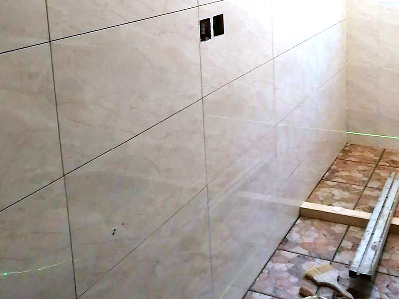 衛(wèi)生間瓷磚鋪貼：基層處理：首先應(yīng)除去基層表面的污垢，油漬，浮灰;除去基層上所有涂料層，膩?zhàn)訉?如果基層未能達(dá)到平整度要求，需對(duì)基層進(jìn)行預(yù)先的找平處理。  放樣：鋪貼瓷磚前需事先找好垂直線，以此為基準(zhǔn)鋪貼的瓷磚高低均勻、垂直美觀;此外，施工前在墻體四周需彈出標(biāo)高控制線，在地面彈出十字線，以控制地磚分隔尺寸。  預(yù)鋪：首先應(yīng)對(duì)瓷磚的色彩、紋理、表面平整等進(jìn)行嚴(yán)格的挑選，然后按照?qǐng)D紙要求預(yù)鋪。 調(diào)制粘結(jié)劑：加水后將粘結(jié)劑漿料攪拌至潤(rùn)滑均勻，無(wú)明顯塊狀或糊狀結(jié)塊，攪拌后的漿料靜置5-10分鐘后再稍加攪拌1-2分鐘即可使用。在開(kāi)始鋪貼施工前，需要先清理瓷磚表面的浮灰，污垢等。  抹漿料：將調(diào)制好的漿料均勻地抹在瓷磚背面，要求漿料飽滿。將瓷磚平整地鋪貼在基層上，使用橡膠錘將瓷磚拍實(shí)鋪平。施工過(guò)程中，可小幅度轉(zhuǎn)動(dòng)瓷磚，使?jié){料與瓷磚背面充分接觸。 瓷磚鋪貼結(jié)束后24小時(shí)，可進(jìn)行嵌縫施工。將調(diào)制好的嵌縫劑均勻地涂在磚與磚的縫隙內(nèi)。嵌縫后用浸濕的織物清理多余的嵌縫劑，保持瓷磚表面清潔。