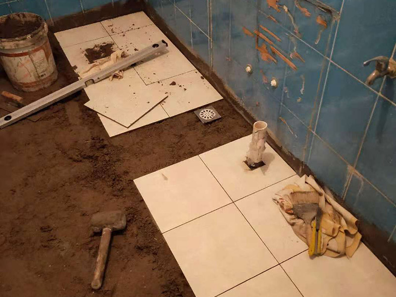 廁所地磚鋪貼維修：1、首先將選購(gòu)好的瓷磚清潔干凈，并在水中浸泡2個(gè)小時(shí)以上，瓷磚的浸泡是為了能讓瓷磚充分的吸收水分，避免在鋪貼完成之后吸取材料中的水分，而影響瓷磚與地面的粘貼度，造成起空鼓、脫落等現(xiàn)象，開始鋪貼瓷磚之前需要從水中取出并將便面的水分擦去，以便鋪貼。 2、在開始瓷磚進(jìn)行鋪貼之前，需先在墻面上吊垂線，吊垂線是用來(lái)確定瓷磚與墻面的尺寸，再設(shè)置水平線，這樣能夠保證瓷磚鋪貼過(guò)程中保持橫平豎直的平整度。 3、在瓷磚鋪貼過(guò)程中需要以水平線為準(zhǔn)繩，設(shè)置木板將瓷磚支撐住，這樣是為了防止瓷磚在達(dá)到一定的粘著強(qiáng)度之前出現(xiàn)位移或下墜的現(xiàn)象。  4.、通常地磚的鋪貼都是由門窗邊或者陽(yáng)臺(tái)開始的，保證從上到下，由左及右的順序行進(jìn)，先用水潤(rùn)曾找平層，再用鏟子將水泥抹在瓷磚的背面，再將瓷磚貼在地面，再用橡膠錘輕輕敲擊瓷磚，使水泥充滿墻面與瓷磚之間的空隙，粘貼時(shí)要注意所使用的粘貼材料不能太稠，也不能太稀，太稠的話不容易攤開，太稀的話又不容易粘牢。 5、當(dāng)?shù)卮u鋪貼好之后，需要及時(shí)將表面的污漬清潔干凈，當(dāng)表面的污染比較嚴(yán)重時(shí)，可以使用10%濃度的稀鹽酸溶液來(lái)進(jìn)行清潔，如果選用稀鹽酸進(jìn)行清洗的話，最后一定要再用清水沖洗一遍。如果是瓷磚釉的話，清理完成之后還可在表面噴上一層薄薄的碧麗珠光亮劑，并且使用軟抹布再擦拭一遍，就能夠保持瓷磚表面的光澤度并且不容易受到污染。