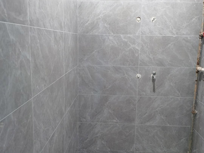 衛(wèi)生間貼磚施工：應(yīng)全部清理墻面上的各類污物，打掃干凈現(xiàn)場，特別是腳落里。用泥刀先批墻，后用水泥漿找平。這個工序很重要，確保底子平，防止貼后空鼓。墻面要刷防水涂料，防止貼后浸水，一般高度不低于1.8米，刷的時候會稍高一些。根據(jù)設(shè)計鋪貼圖樣的要求，確定排磚方案，用墨斗彈線，以減少施工損耗。把剛剛攪拌好的粘結(jié)劑漿料均勻的刮到墻上。瓷磚上墻將經(jīng)過預(yù)先清潔的瓷磚平整地鋪貼在粘結(jié)劑漿料基層上，使用橡膠錘將瓷磚拍實鋪平。施工過程中，可小幅度轉(zhuǎn)動瓷磚，使?jié){料與瓷磚背面充分接觸。專家建議在鋪貼時，隨機(jī)取下已鋪貼于基層上的瓷磚作檢查。確保漿料與瓷磚背面的充分接觸。 留縫大小調(diào)整根據(jù)瓷磚的尺寸，在磚與磚之間預(yù)留相應(yīng)尺寸的縫隙留待嵌縫。可用牙簽等先固定，粘結(jié)劑具有一定的可調(diào)整性，可對留縫的大小進(jìn)行調(diào)整。