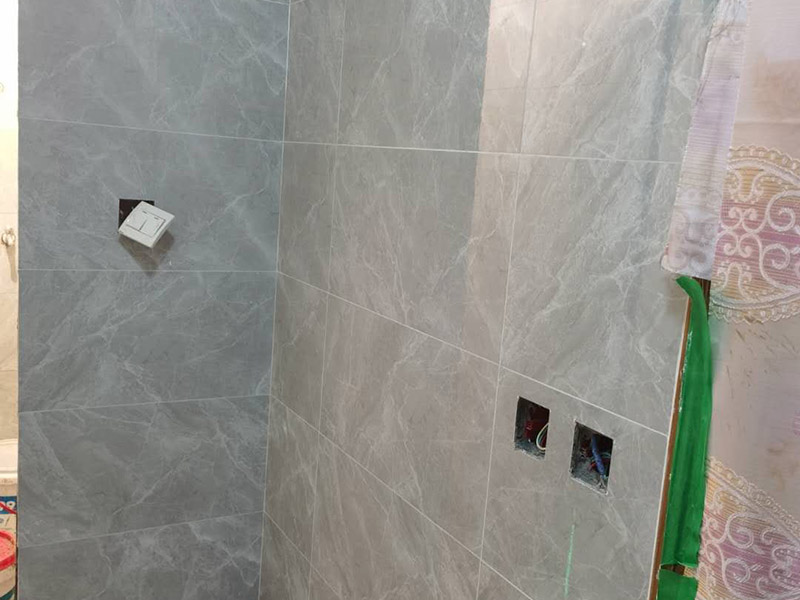 衛(wèi)生間貼磚施工：應(yīng)全部清理墻面上的各類污物，打掃干凈現(xiàn)場，特別是腳落里。用泥刀先批墻，后用水泥漿找平。這個工序很重要，確保底子平，防止貼后空鼓。墻面要刷防水涂料，防止貼后浸水，一般高度不低于1.8米，刷的時候會稍高一些。根據(jù)設(shè)計鋪貼圖樣的要求，確定排磚方案，用墨斗彈線，以減少施工損耗。把剛剛攪拌好的粘結(jié)劑漿料均勻的刮到墻上。瓷磚上墻將經(jīng)過預(yù)先清潔的瓷磚平整地鋪貼在粘結(jié)劑漿料基層上，使用橡膠錘將瓷磚拍實鋪平。施工過程中，可小幅度轉(zhuǎn)動瓷磚，使?jié){料與瓷磚背面充分接觸。專家建議在鋪貼時，隨機(jī)取下已鋪貼于基層上的瓷磚作檢查。確保漿料與瓷磚背面的充分接觸。 留縫大小調(diào)整根據(jù)瓷磚的尺寸，在磚與磚之間預(yù)留相應(yīng)尺寸的縫隙留待嵌縫?？捎醚篮灥认裙潭ǎ辰Y(jié)劑具有一定的可調(diào)整性，可對留縫的大小進(jìn)行調(diào)整。