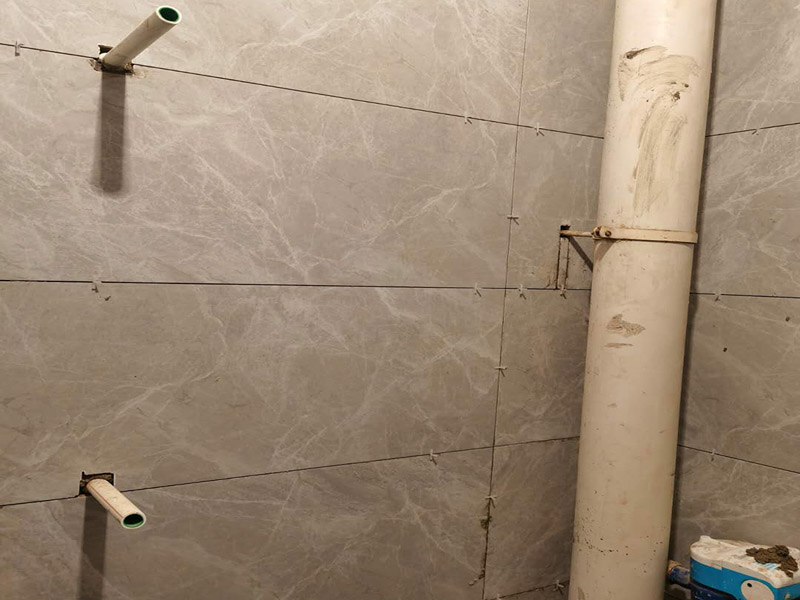 衛(wèi)生間貼磚施工：應(yīng)全部清理墻面上的各類污物，打掃干凈現(xiàn)場，特別是腳落里。用泥刀先批墻，后用水泥漿找平。這個工序很重要，確保底子平，防止貼后空鼓。墻面要刷防水涂料，防止貼后浸水，一般高度不低于1.8米，刷的時候會稍高一些。根據(jù)設(shè)計鋪貼圖樣的要求，確定排磚方案，用墨斗彈線，以減少施工損耗。把剛剛攪拌好的粘結(jié)劑漿料均勻的刮到墻上。瓷磚上墻將經(jīng)過預(yù)先清潔的瓷磚平整地鋪貼在粘結(jié)劑漿料基層上，使用橡膠錘將瓷磚拍實鋪平。施工過程中，可小幅度轉(zhuǎn)動瓷磚，使?jié){料與瓷磚背面充分接觸。專家建議在鋪貼時，隨機(jī)取下已鋪貼于基層上的瓷磚作檢查。確保漿料與瓷磚背面的充分接觸。 留縫大小調(diào)整根據(jù)瓷磚的尺寸，在磚與磚之間預(yù)留相應(yīng)尺寸的縫隙留待嵌縫?？捎醚篮灥认裙潭?，粘結(jié)劑具有一定的可調(diào)整性，可對留縫的大小進(jìn)行調(diào)整。