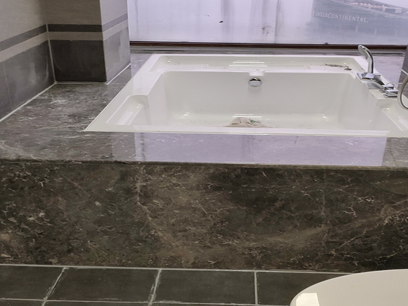 浴缸貼磚安裝：在安放浴缸時注意下水口的另一端要略高于下水口的一端，以便將來排污不暢。這一點要因情況而定。一般正常的浴缸底部本來就留出了排水的坡度。在安放浴缸時注意下水口的另一端要略高于下水口的一端，以便將來排污不暢。這一點要因情況而定。一般正常的浴缸底部本來就留出了排水的坡度。浴缸裙的貼磚是不需要抓毛的，砌好紅磚的臺子，在表面抹一層水泥砂漿，然后等兩天再來貼磚即可，貼磚很麻煩，由于地面留了坡度，而浴缸是平的，所以每一塊大磚都要打磨成不同的尺寸，不可以一次打磨很多，容易磨多了，要反復(fù)磨。磚的上邊要塞入浴缸的圓邊下，這樣才不會形成陽角。