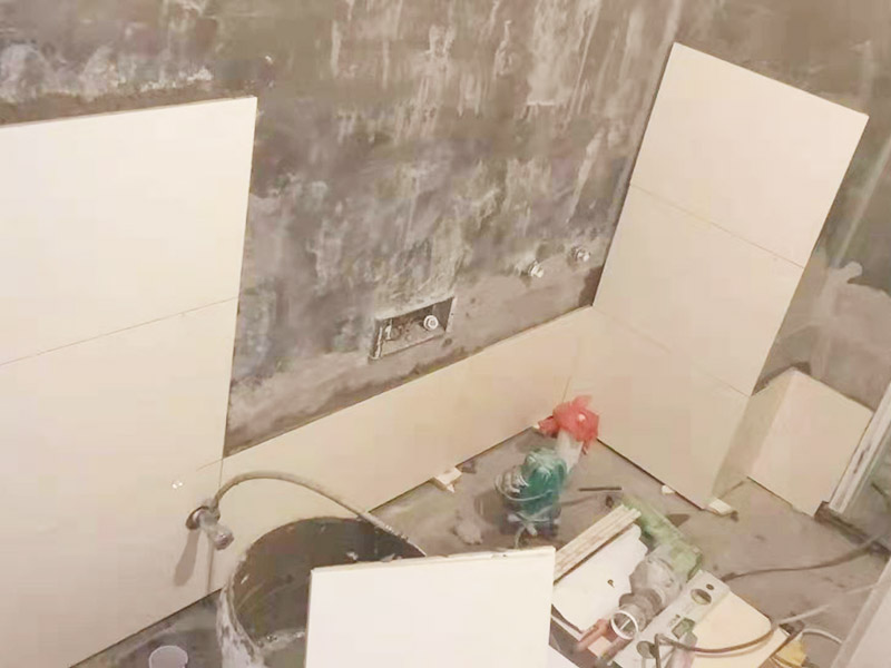 衛(wèi)生間墻面貼磚：首先應(yīng)除去基層表面的污垢，油漬，浮灰;除去基層上所有涂料層，膩子層;如果基層未能達(dá)到平整度要求，需對基層進(jìn)行預(yù)先的找平處理。鋪貼瓷磚前需事先找好垂直線，以此為基準(zhǔn)鋪貼的瓷磚高低均勻、垂直美觀;此外，施工前在墻體四周需彈出標(biāo)高控制線，在地面彈出十字線，以控制地磚分隔尺寸。對瓷磚的色彩、紋理、表面平整等進(jìn)行嚴(yán)格的挑選，然后按照圖紙要求預(yù)鋪。對可能出現(xiàn)的尺寸、色彩、紋理誤差等進(jìn)行調(diào)整、交換，直至達(dá)到最佳效果。 調(diào)制粘結(jié)劑：加水后將粘結(jié)劑漿料攪拌至潤滑均勻，無明顯塊狀或糊狀結(jié)塊，攪拌后的漿料靜置5-10分鐘后再稍加攪拌1-2分鐘即可使用。 將瓷磚平整地鋪貼在基層上，使用橡膠錘將瓷磚拍實鋪平。施工過程中，可小幅度轉(zhuǎn)動瓷磚，使?jié){料與瓷磚背面充分接觸。