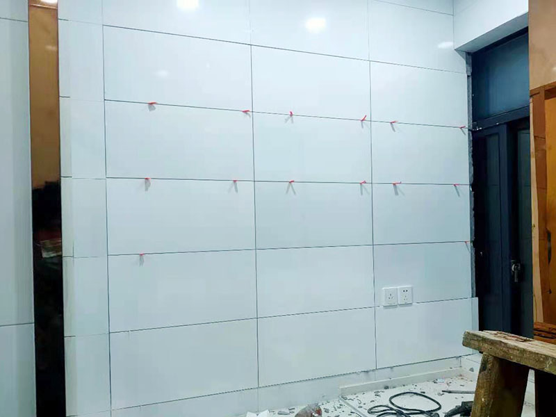 墻磚鋪貼施工：基層處理：保持墻面的平滑，踢平表面凹凸不平的位置或用1:3比例的水泥漿抹平，用鐵絲擦掉殘留的灰塵、油漬、砂漿等。 找標高、彈線：根據水平控制線和設計圖紙劃出標高，再拋出十字線并保持墻面一線和地面一線垂直。 預鋪：在圖紙設計要求的基礎上，嚴格挑選墻磚的色彩、紋理等，然后進行預鋪，對于預鋪效果中可能出現(xiàn)的紋理、尺寸、色差進行調整、更換，直到達到最佳效果。 貼磚：貼磚選用1：3比例的干硬性水泥砂漿，砂漿厚度2cm左右。鋪貼前將墻磚背面濕潤，正面保持干燥。把墻磚輕輕地放在水泥砂漿上，用手錘輕敲瓷磚表面直至緊密平整即可。 勾縫、擦縫：在貼完磚24小時后進行勾縫工作，采用同一品種的水泥漿或專用填縫劑進行空隙填補，使墻磚最終緊密嚴實，最后再擦凈多余的水泥或填縫劑。