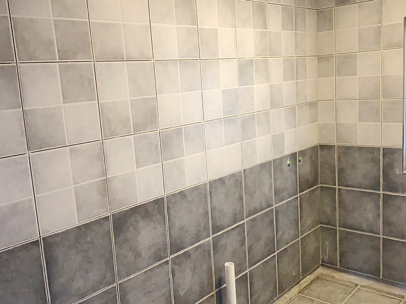 衛(wèi)生間墻磚鋪貼：首先應除去基層表面的污垢，油漬，浮灰;除去基層上所有涂料層，膩子層;如果基層未能達到平整度要求，需對基層進行預先的找平處理。鋪貼瓷磚前需事先找好垂直線，以此為基準鋪貼的瓷磚高低均勻、垂直美觀;此外，施工前在墻體四周需彈出標高控制線，在地面彈出十字線，以控制地磚分隔尺寸。調(diào)制粘結(jié)劑：加水后將粘結(jié)劑漿料攪拌至潤滑均勻，無明顯塊狀或糊狀結(jié)塊，攪拌后的漿料靜置5-10分鐘后再稍加攪拌1-2分鐘即可使用。 將瓷磚平整地鋪貼在基層上，使用橡膠錘將瓷磚拍實鋪平。施工過程中，可小幅度轉(zhuǎn)動瓷磚，使?jié){料與瓷磚背面充分接觸。